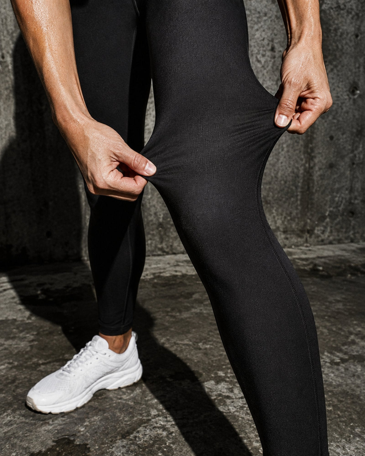 Mains qui étirent le tissu noir du legging, toujours opaque